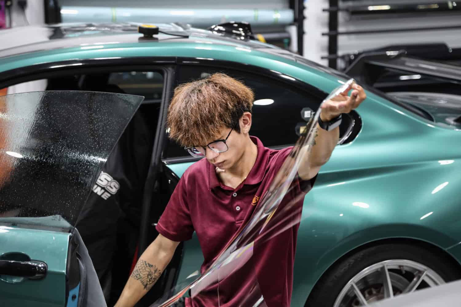 Solar Film Tinting Application Technician applying solar film tinting on car window at Singapore auto shop.